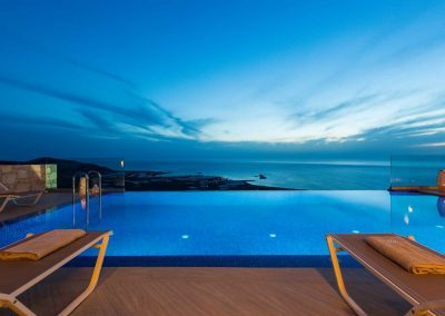 Night time view over infinity pool to sea